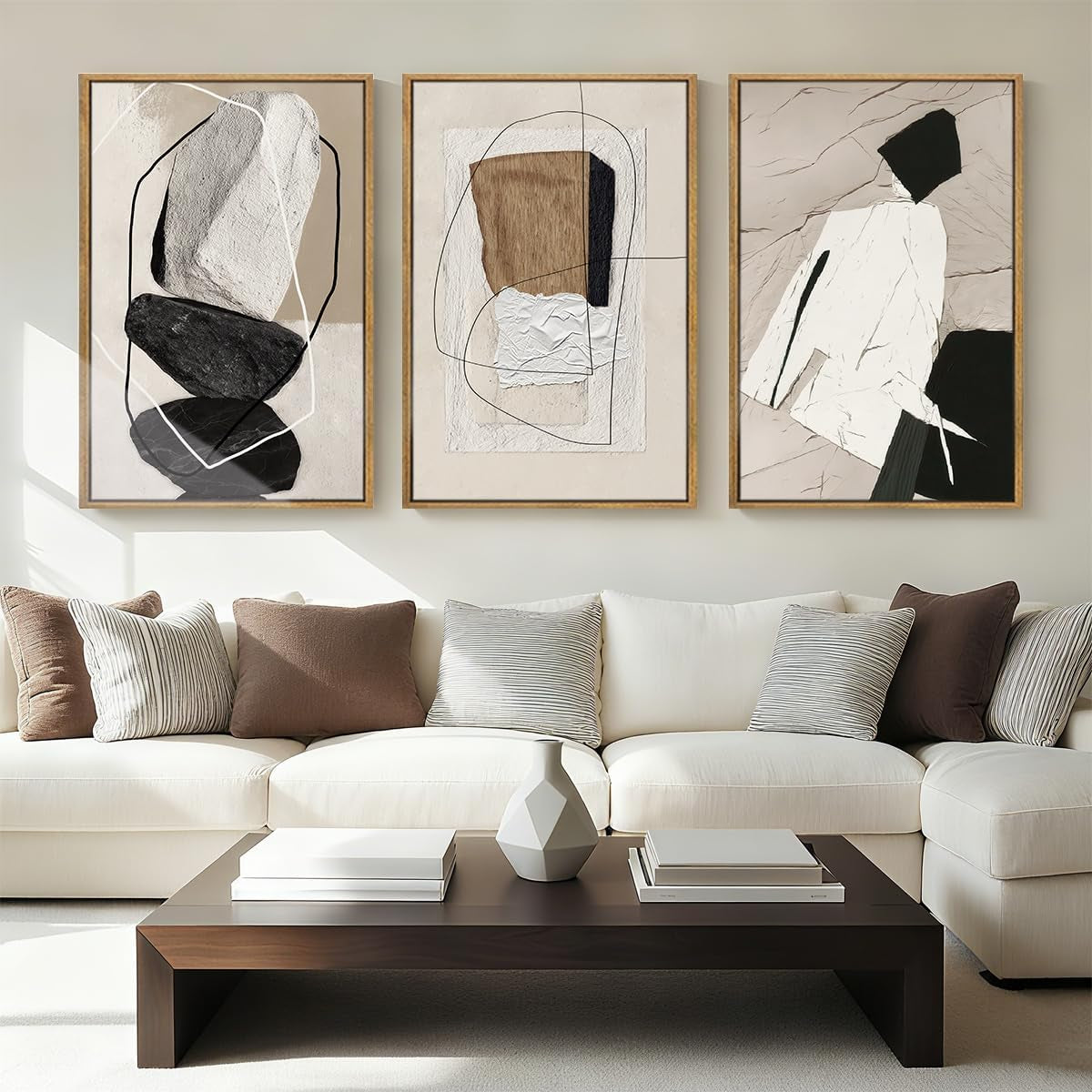 Three framed neutral abstract collage prints with stone and tan textures hung above a cream sectional sofa and coffee table.