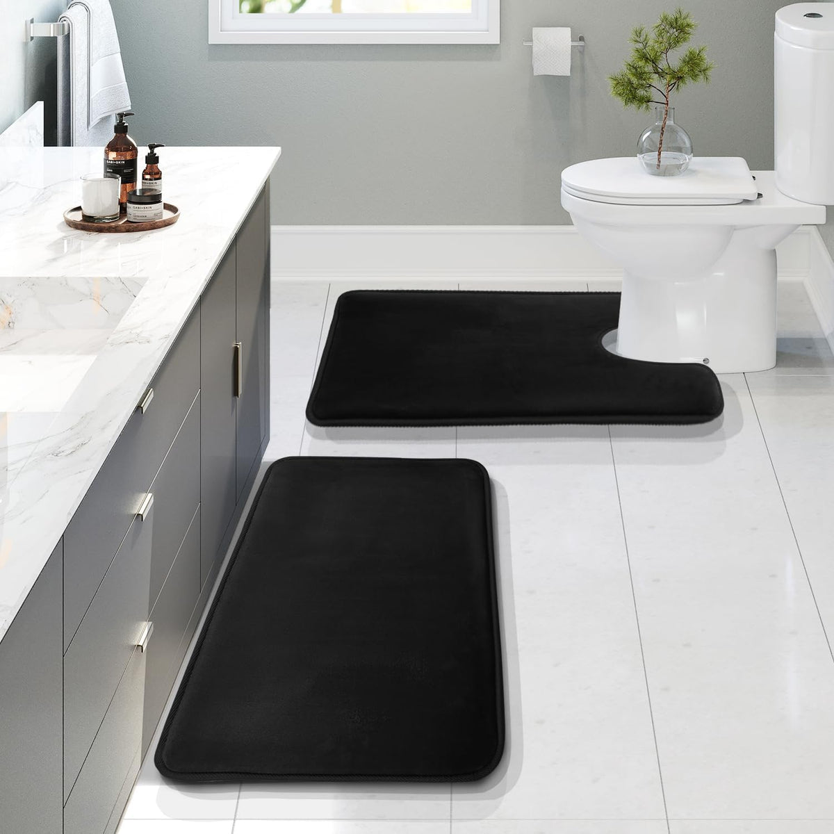 Bathroom scene with two black velvet bath rugs placed along a vanity and U-shaped rug around the toilet.