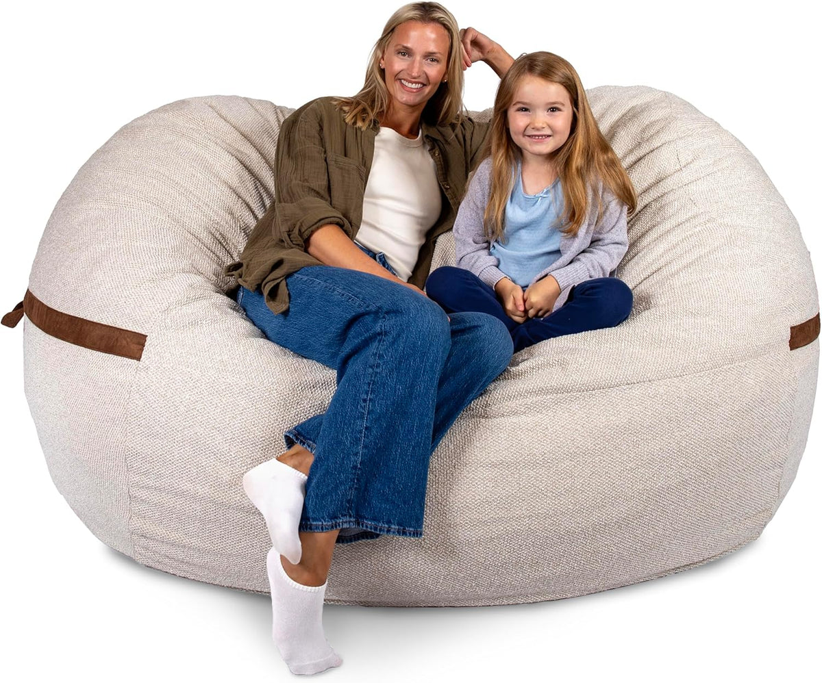 Woman and young girl seated together in the center of a large beige lounger, showing seating scale