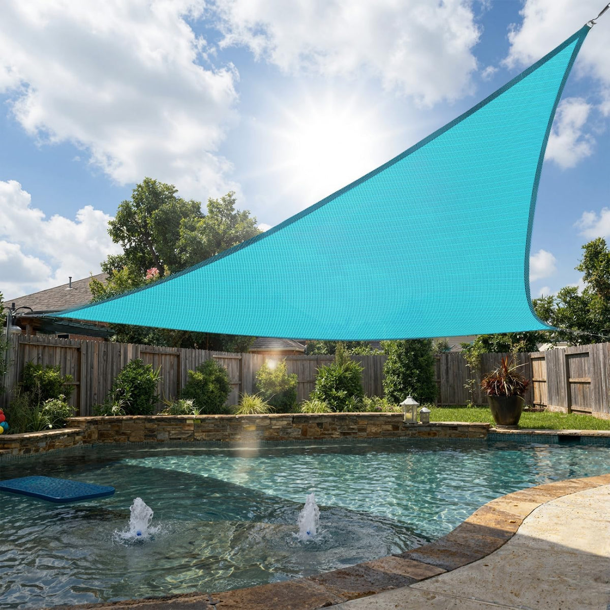 Turquoise triangular shade sail stretched over a backyard pool, angled front view