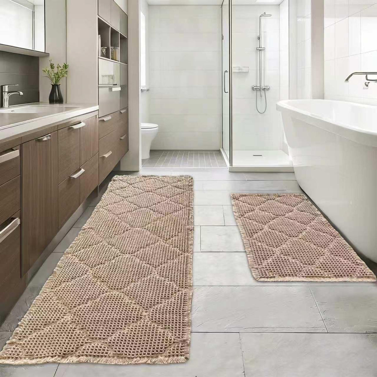 Two tan waffle-texture bathroom mats placed by a bathtub and vanity on a tiled floor in a modern bathroom.