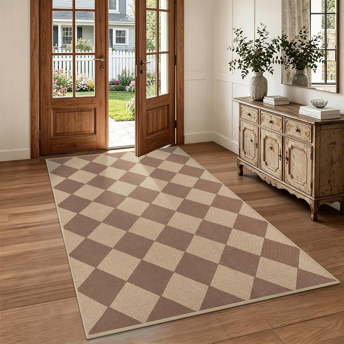Brown and beige diamond-check rug in an entryway beside an antique console with vase and mirror.