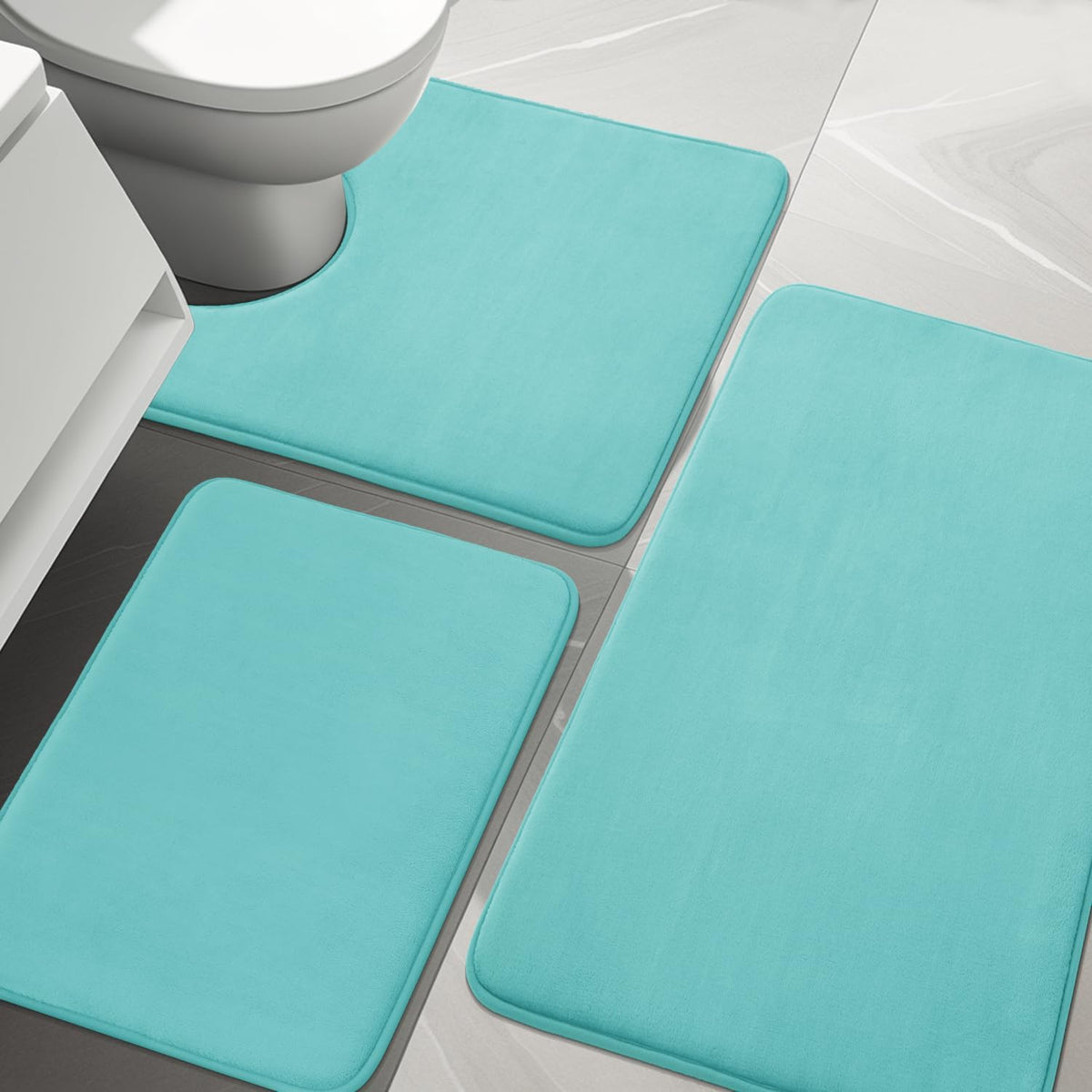 Close top view of three turquoise rectangular memory-foam bath rugs around a toilet base.