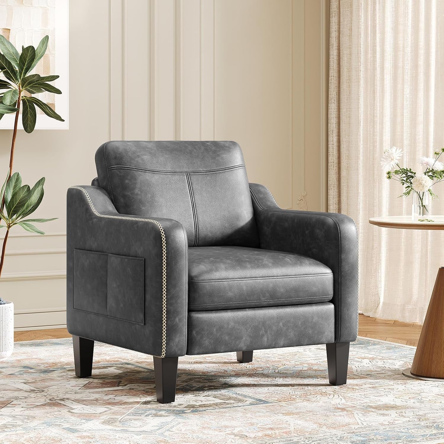 Single dark gray PU leather armchair shown at a three-quarter angle in a styled living room.