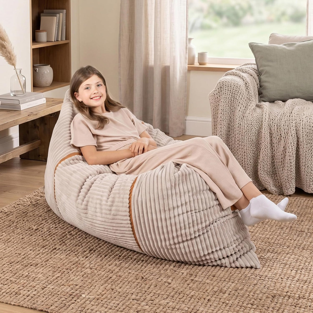 Smiling girl reclining on a light beige ribbed lounger in a neutral living room setting