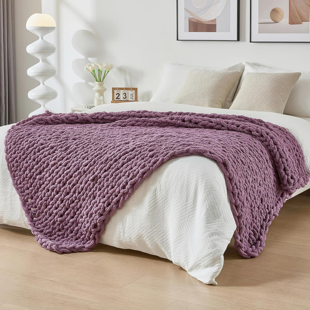 Lavender chunky knit throw spread across the foot of a white-made bed in a bedroom scene