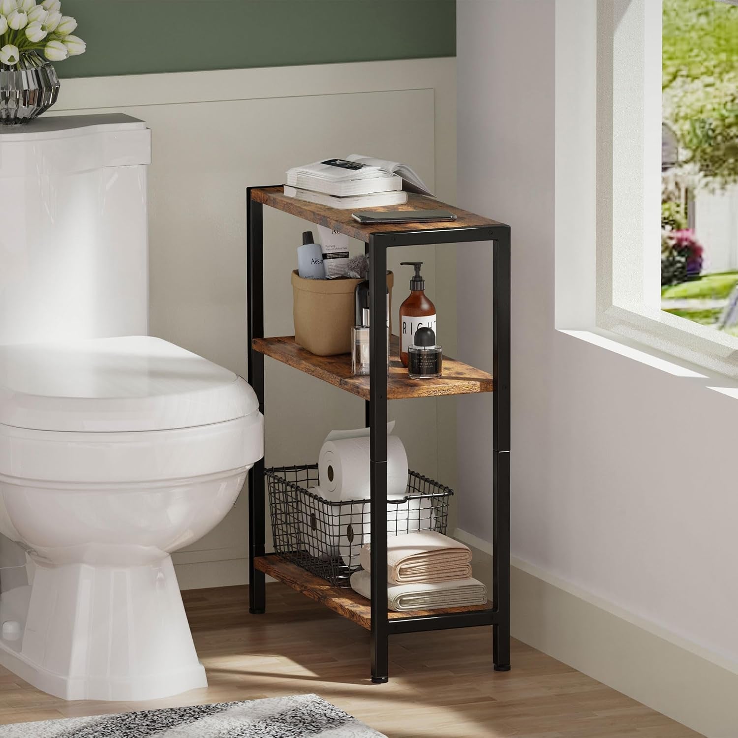 Narrow three-shelf side table placed beside a toilet, holding toiletries and a basket on lower shelf.