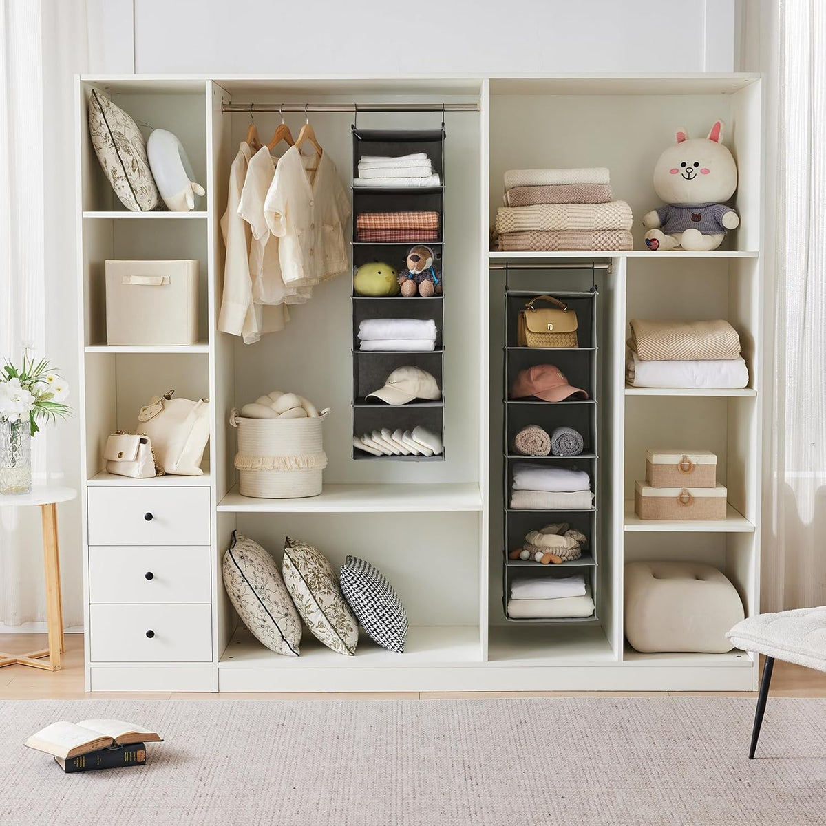 Built-in closet with two grey hanging organizers on a rod holding folded towels, hats and small accessories