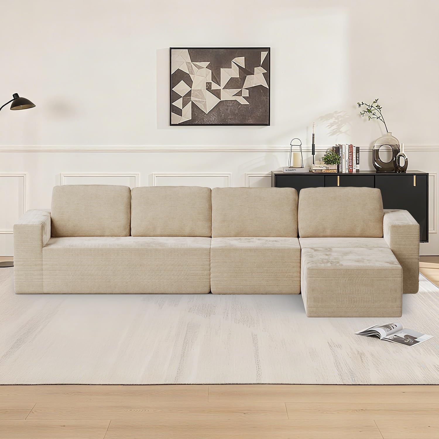 Straight-on living room view of a beige L-shaped modular sofa on a light rug under wall art