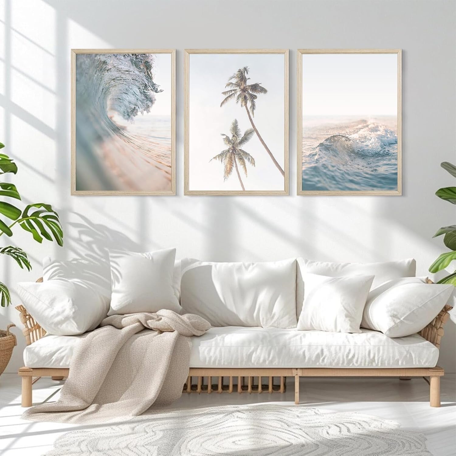 Bright living room with a low wooden sofa and three coastal prints aligned in a row above it, sunlight casting shadows on