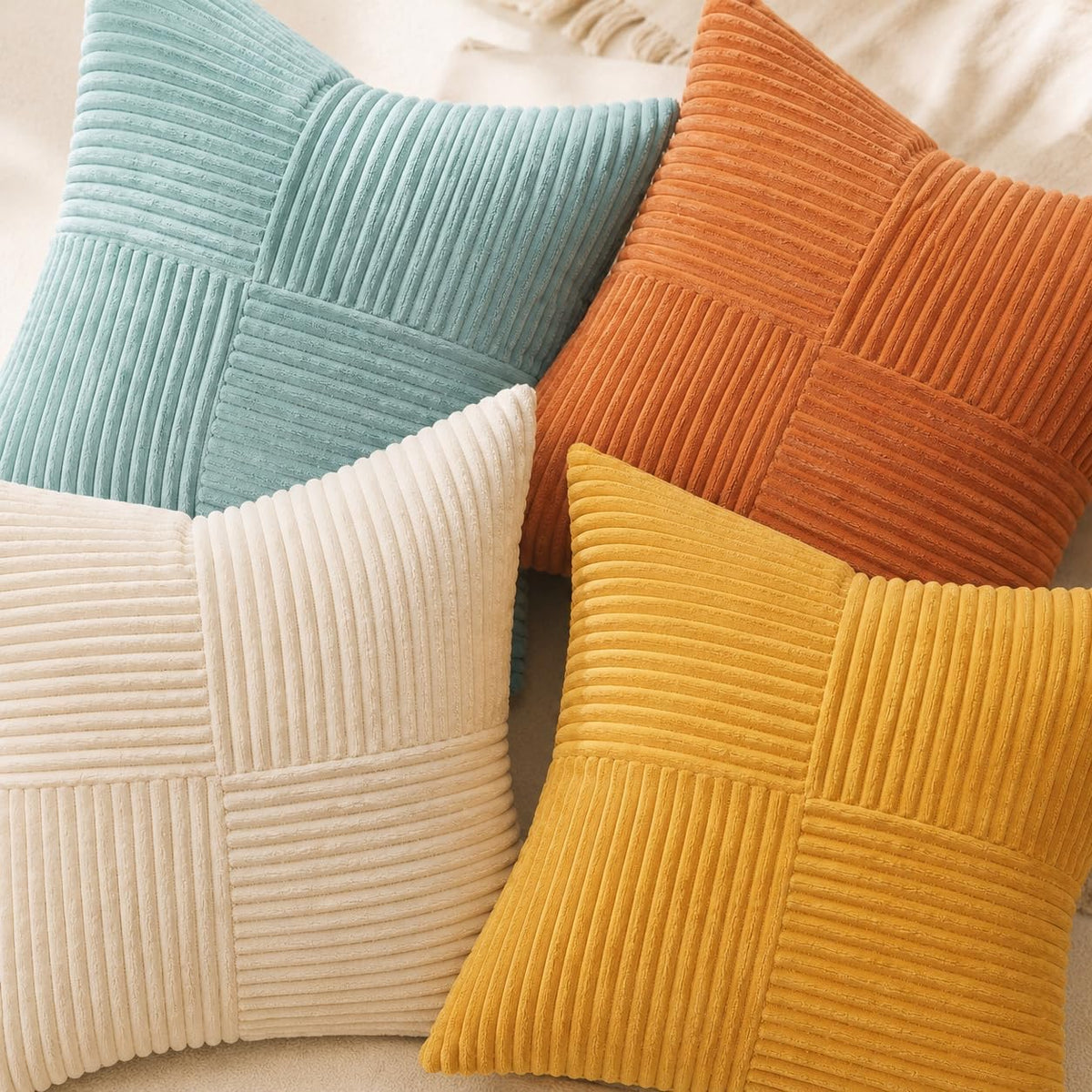 Close-up of four ribbed velvet pillow covers showing corded texture in teal, rust, cream and mustard.