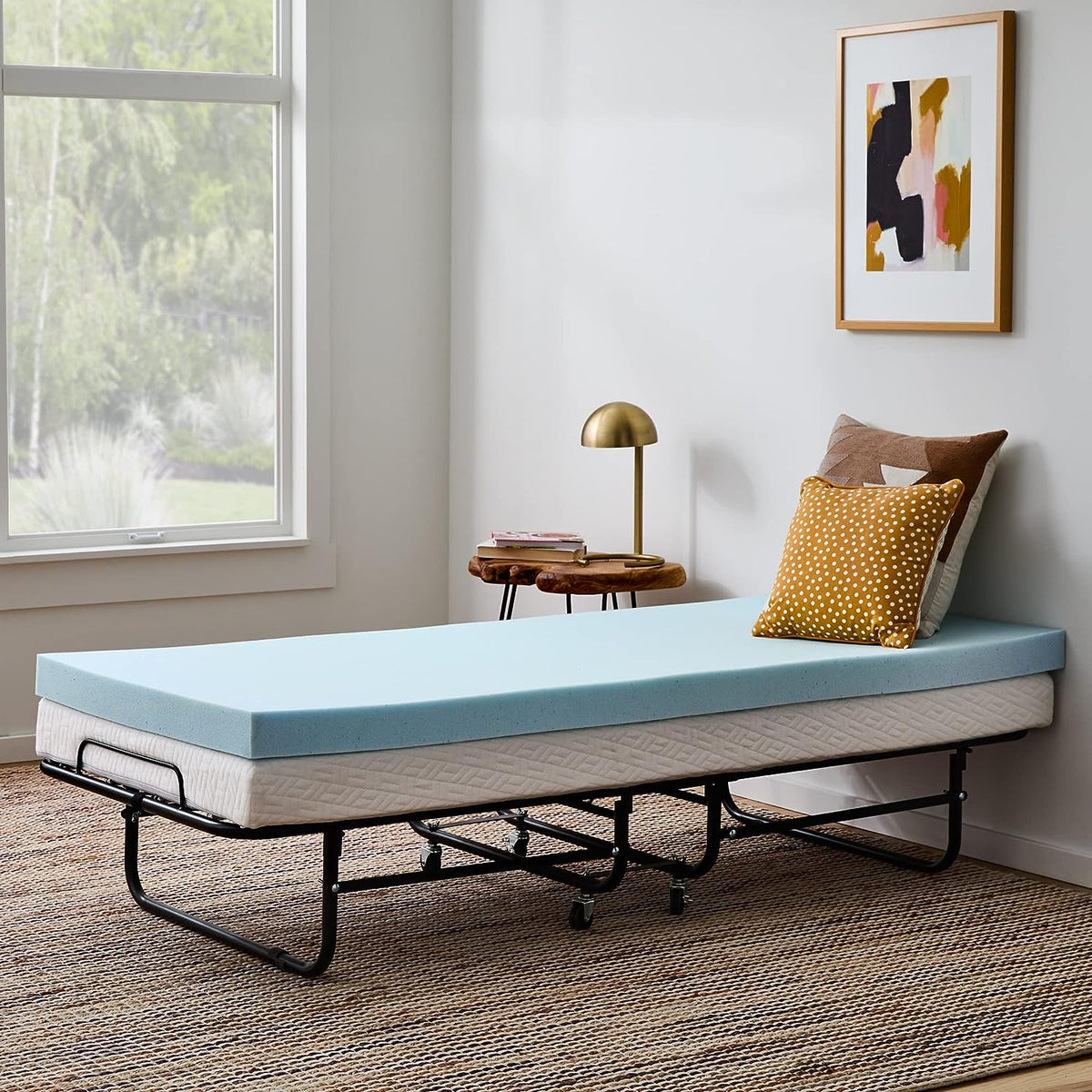 Light blue foam topper placed flat on a fold-out metal bed base with stacked pillows at the head.