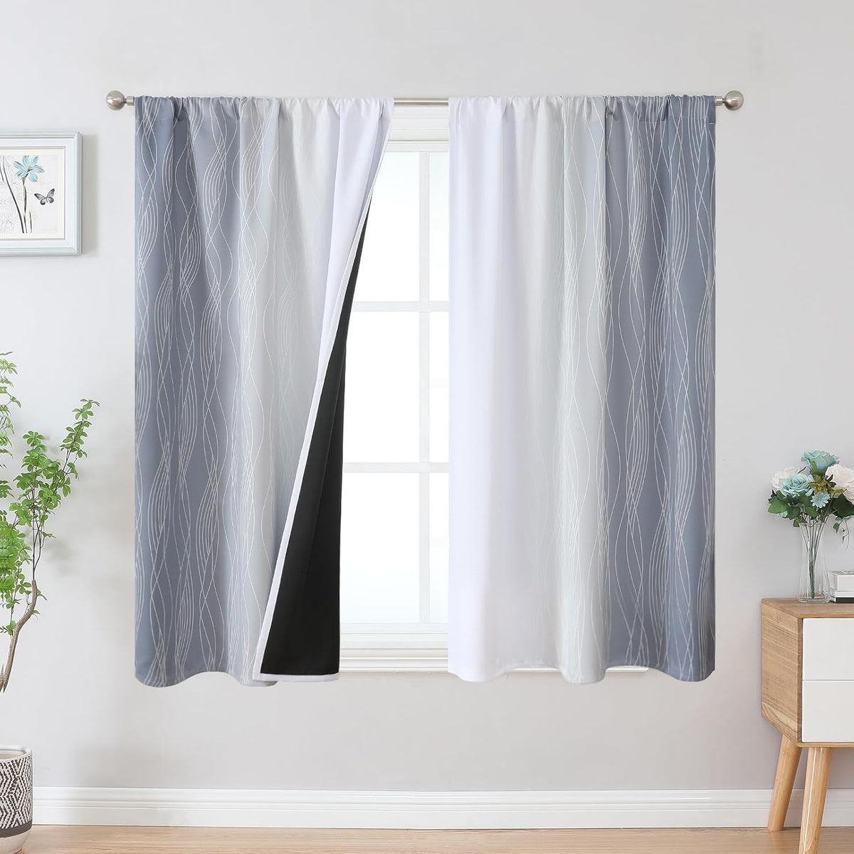 Window with gray-to-white ombre curtains featuring wavy lines and a black blackout backing visible on one panel.