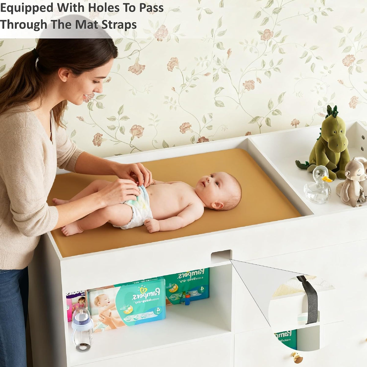 Top view of a white changing table with a baby on a tan changing pad and toys on the side shelf.