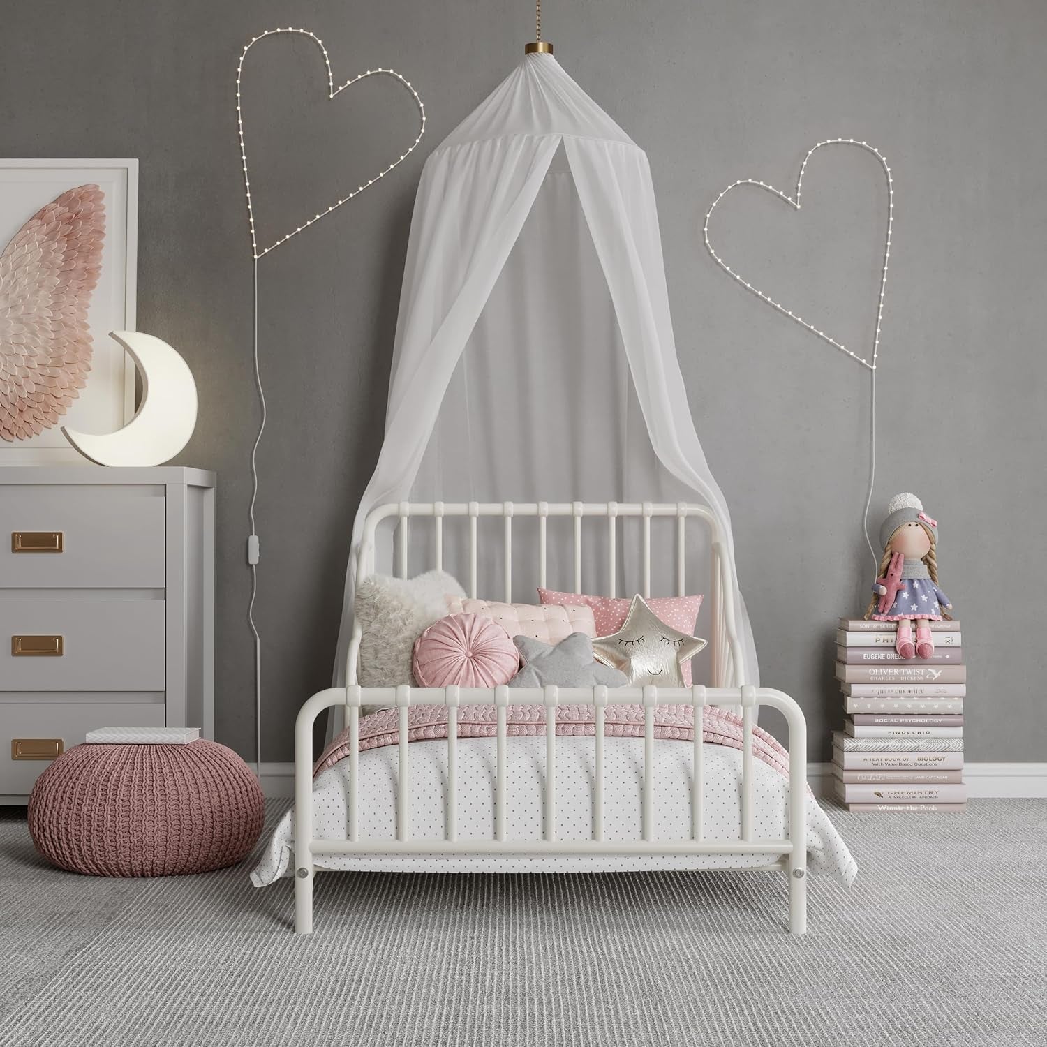 Front-facing view of the off-white metal toddler bed with canopy, pillows and decorative lights.
