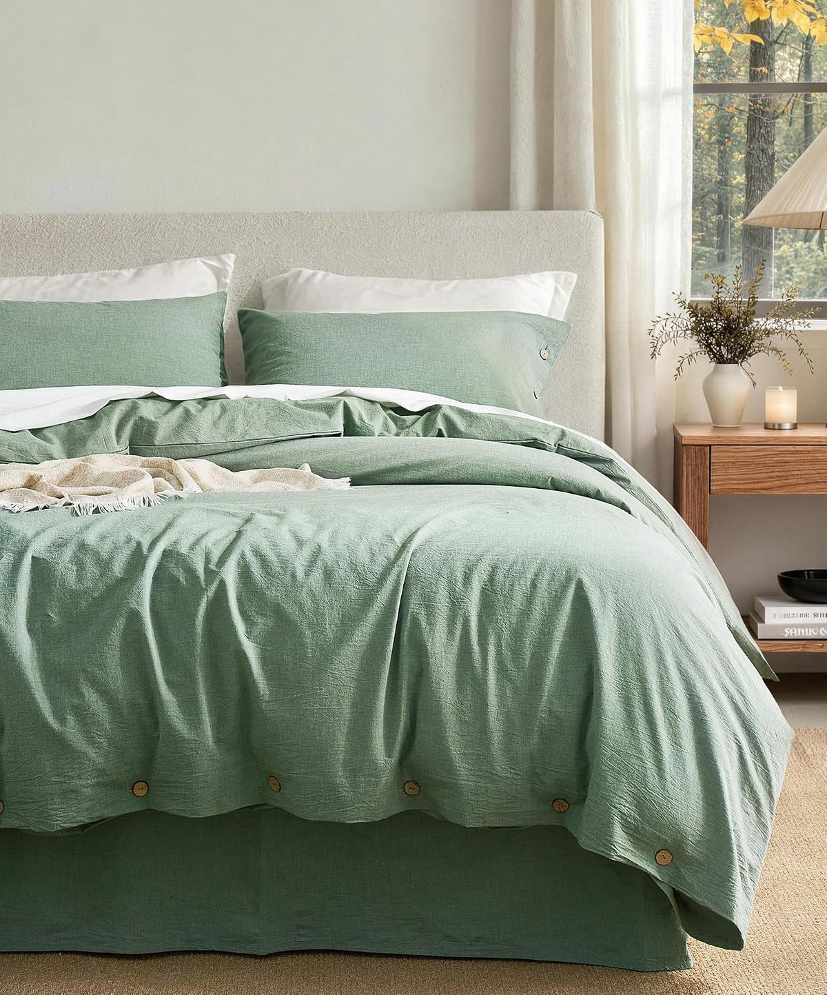 Bed dressed in muted green washed-cotton duvet with matching shams and a neutral headboard