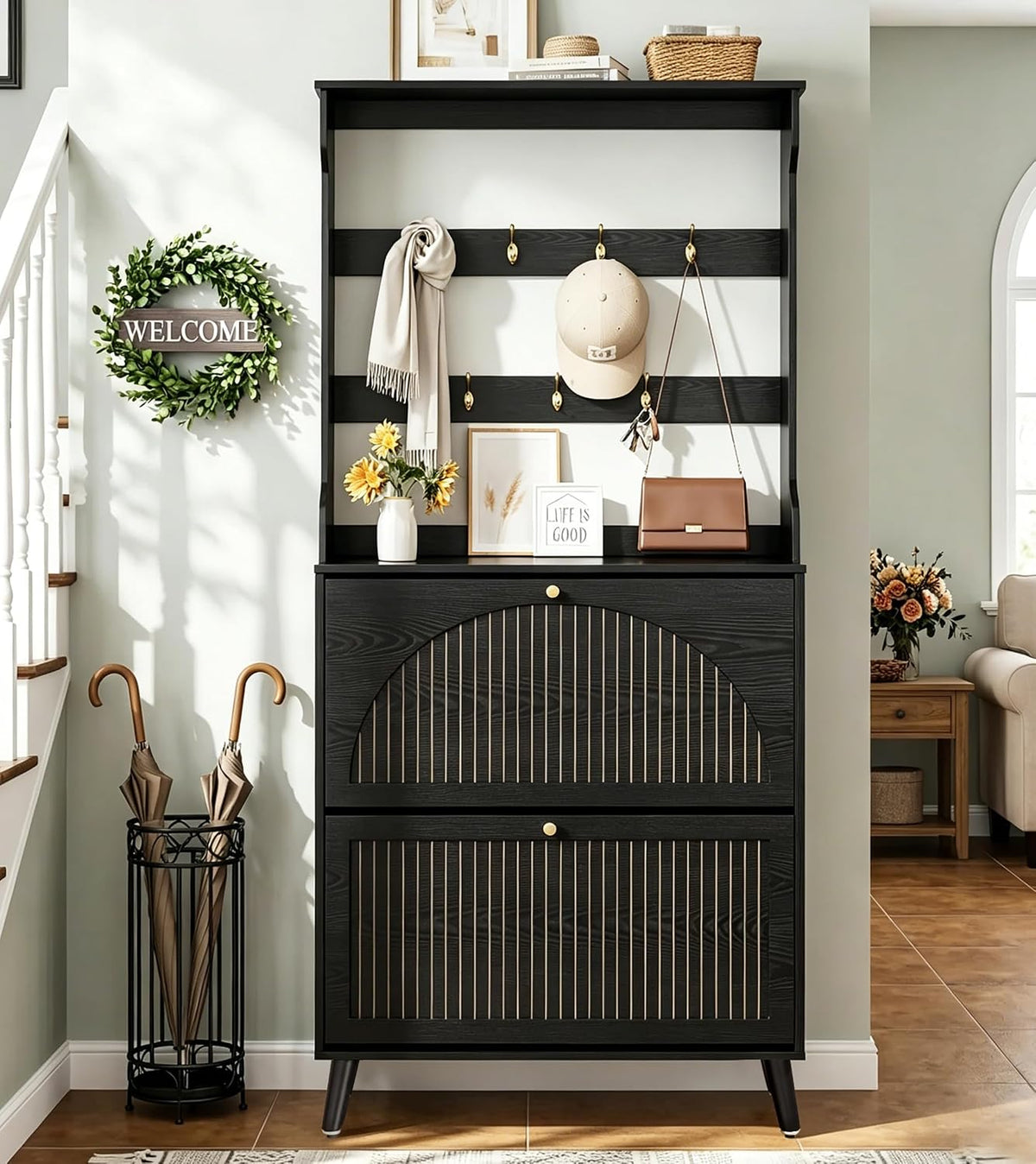 Black shoe cabinet with gold accents, two flip drawers and a slatted hook panel styled by a staircase