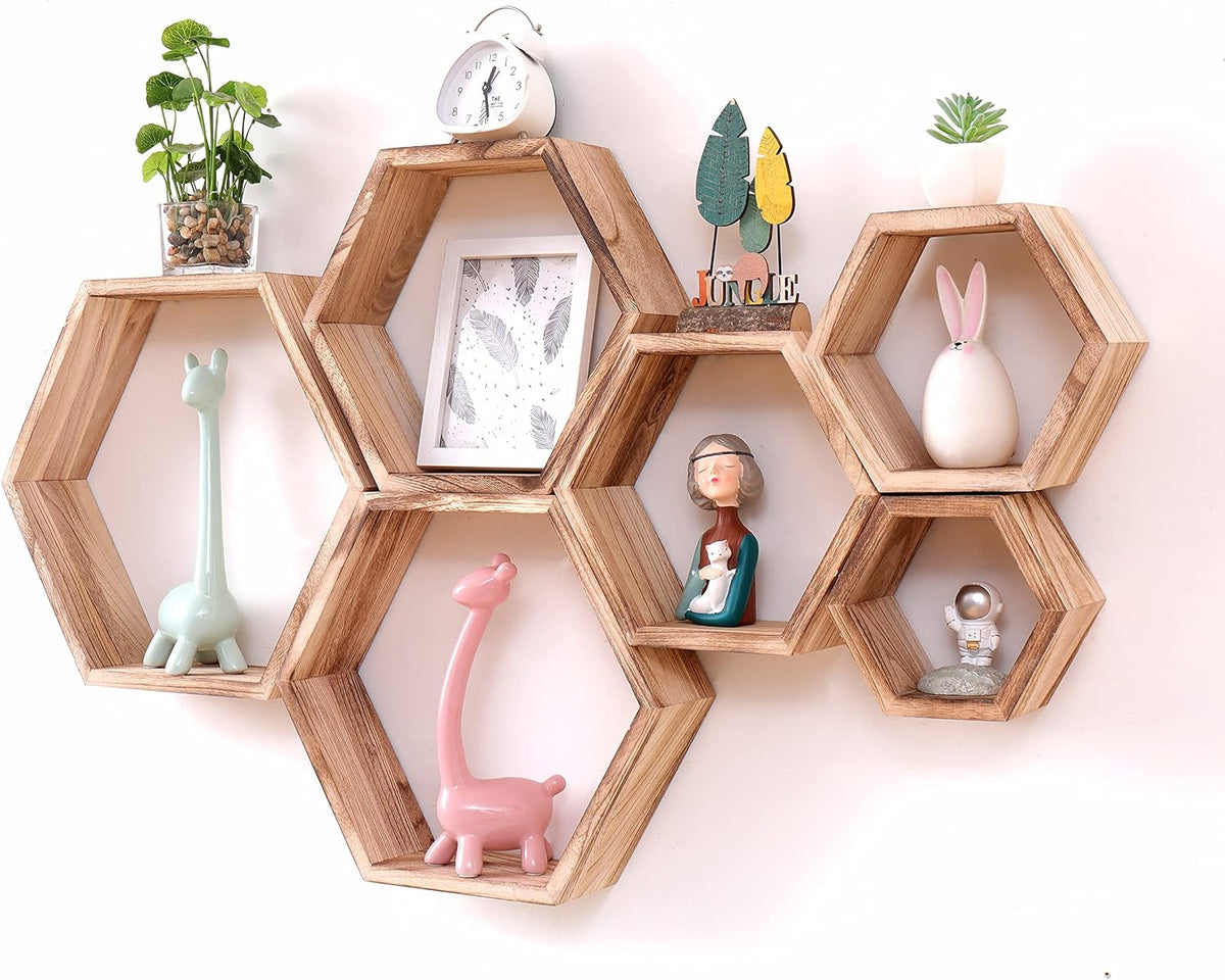 Light wood hexagon shelves mounted on a wall filled with small plants and decorative figurines