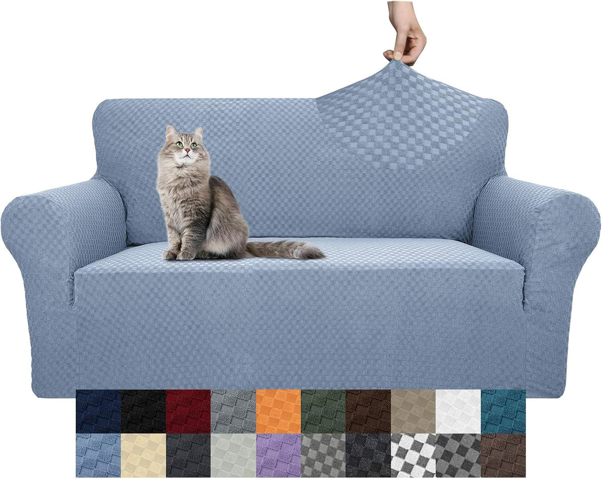 Light blue textured stretch slipcover on a two-seat sofa with a gray cat on the cushion and a hand pulling the cover at the