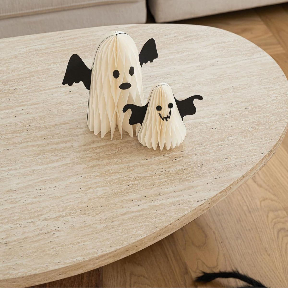 Close-up of travertine-style tabletop surface with two small decorative paper ghost figures