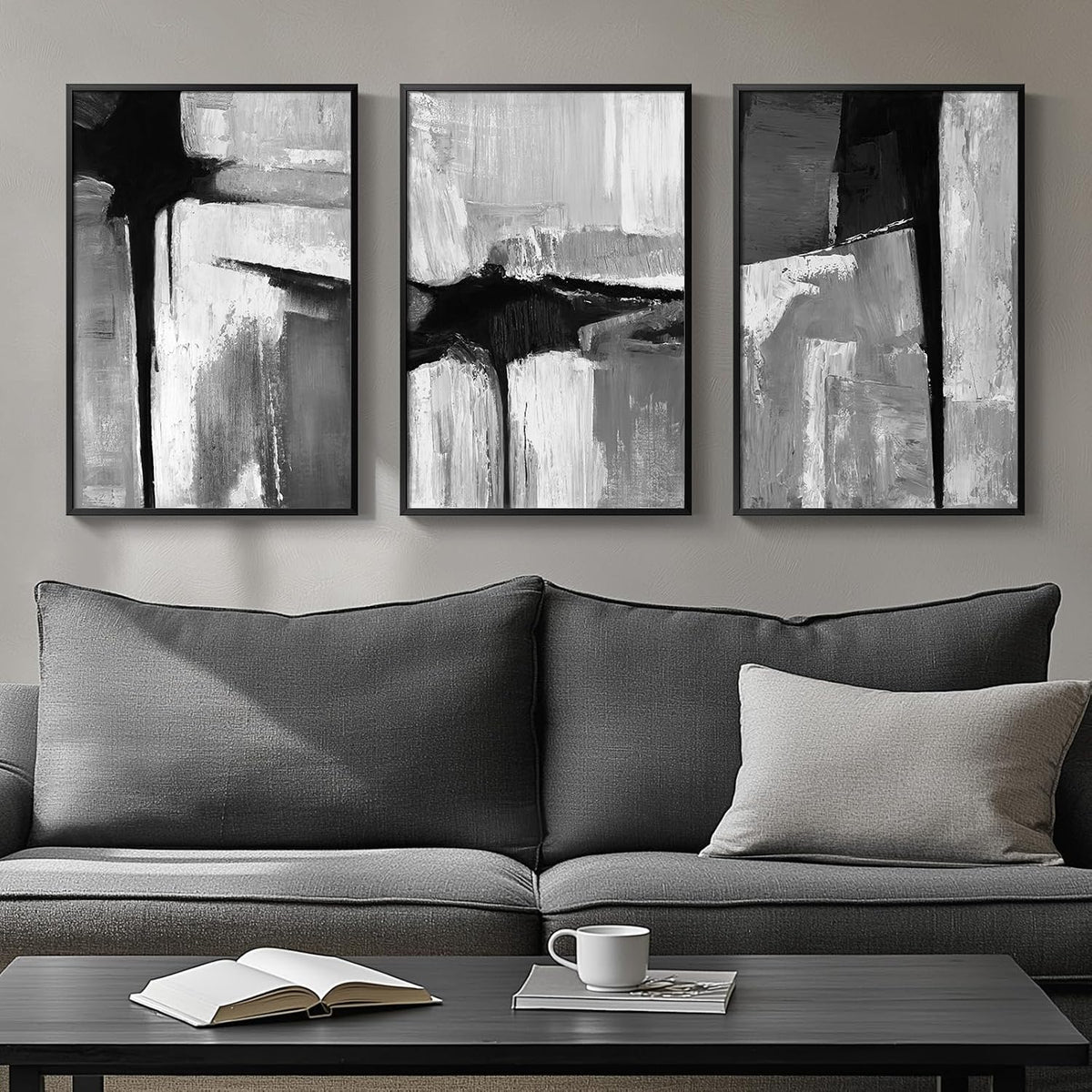 Triptych of black-and-white textured abstract paintings in thin black frames above a dark gray couch.