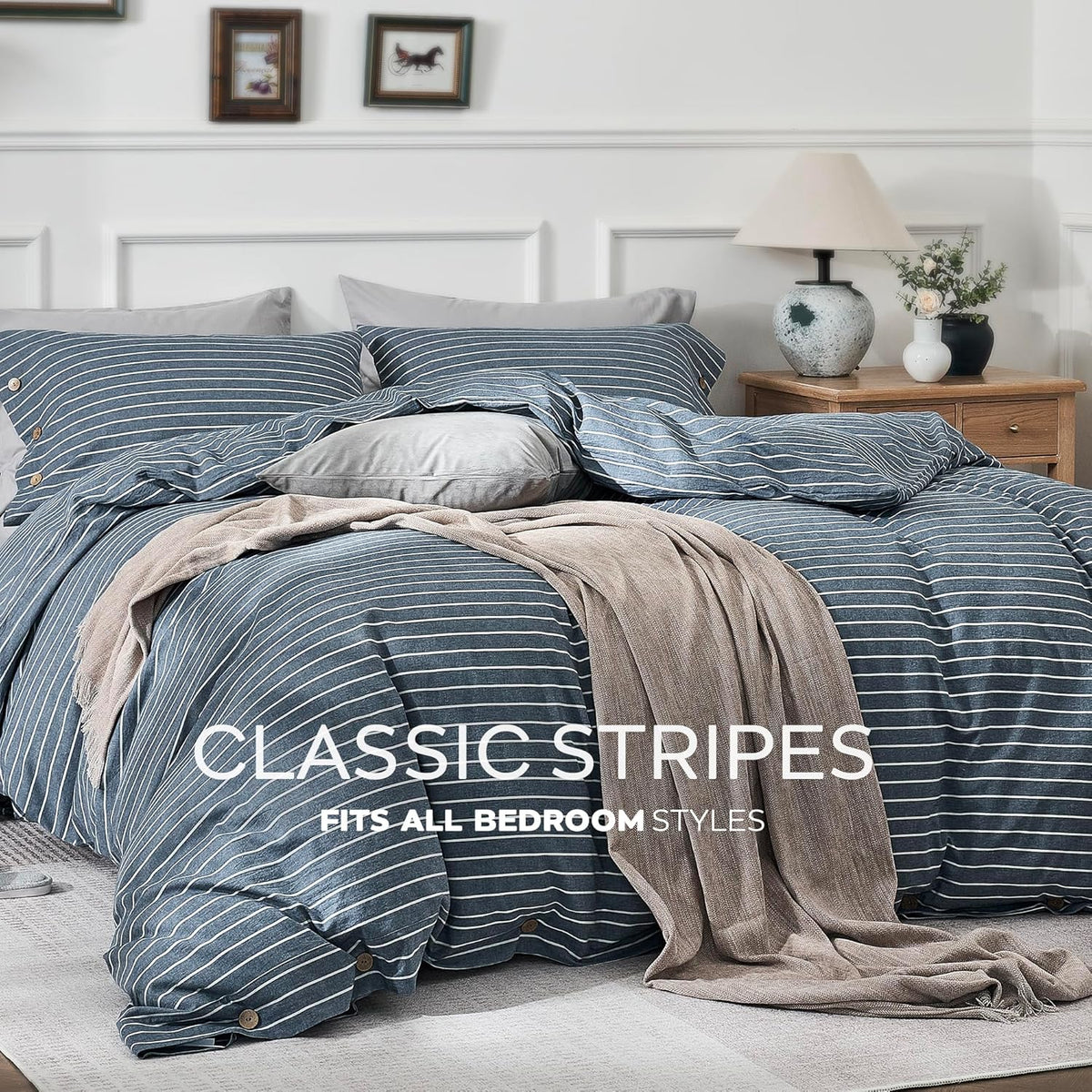 Front view of bed dressed in blue-and-white striped duvet with a beige throw and bedside table lamp.