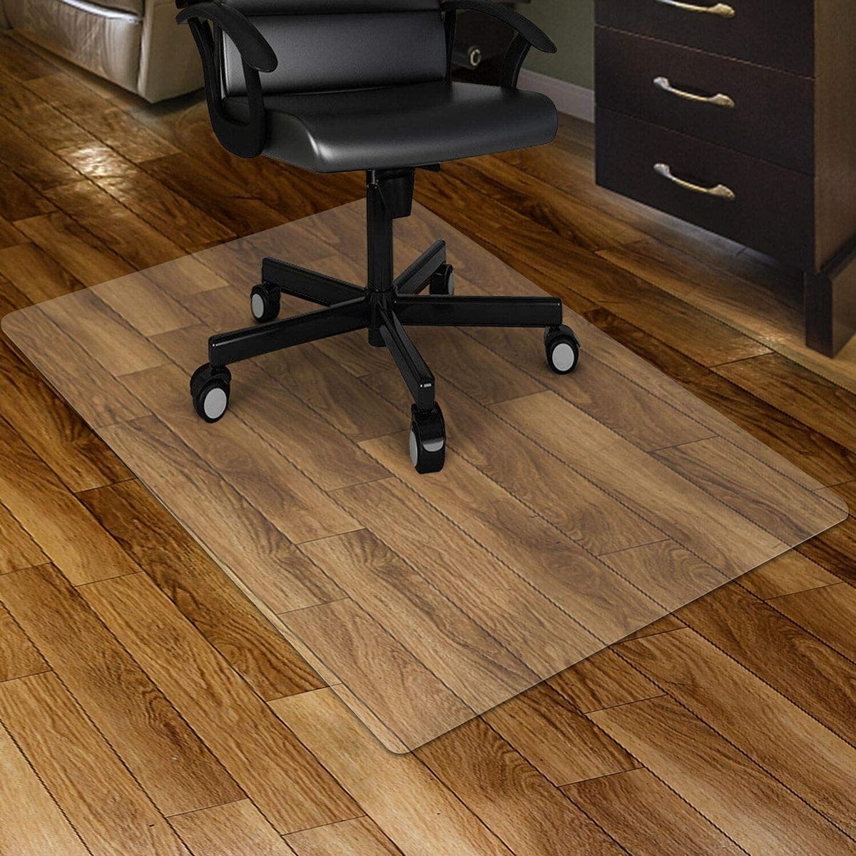 Clear rectangular PVC chair mat under a black office chair on a medium wood floor, angled front view