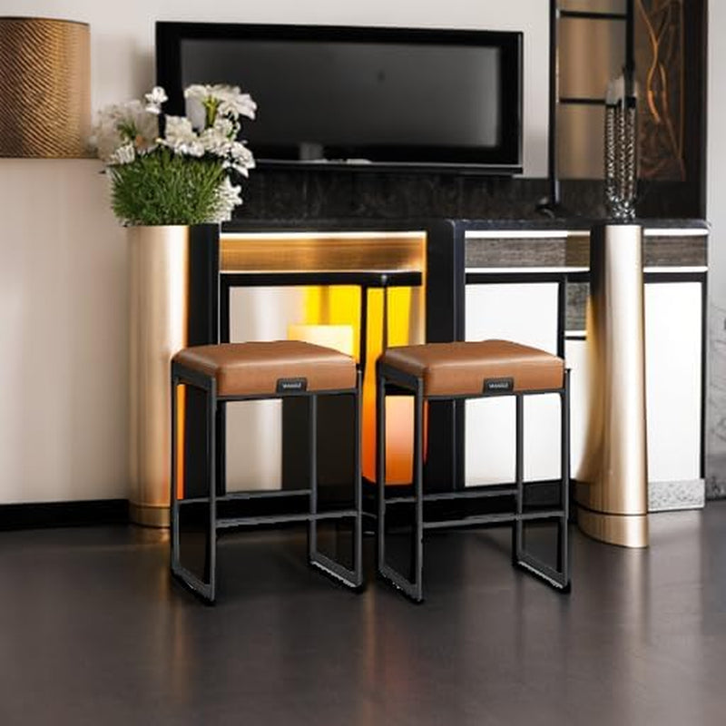 Pair of caramel cushioned stools with matte black frames placed by a home bar area, angled view