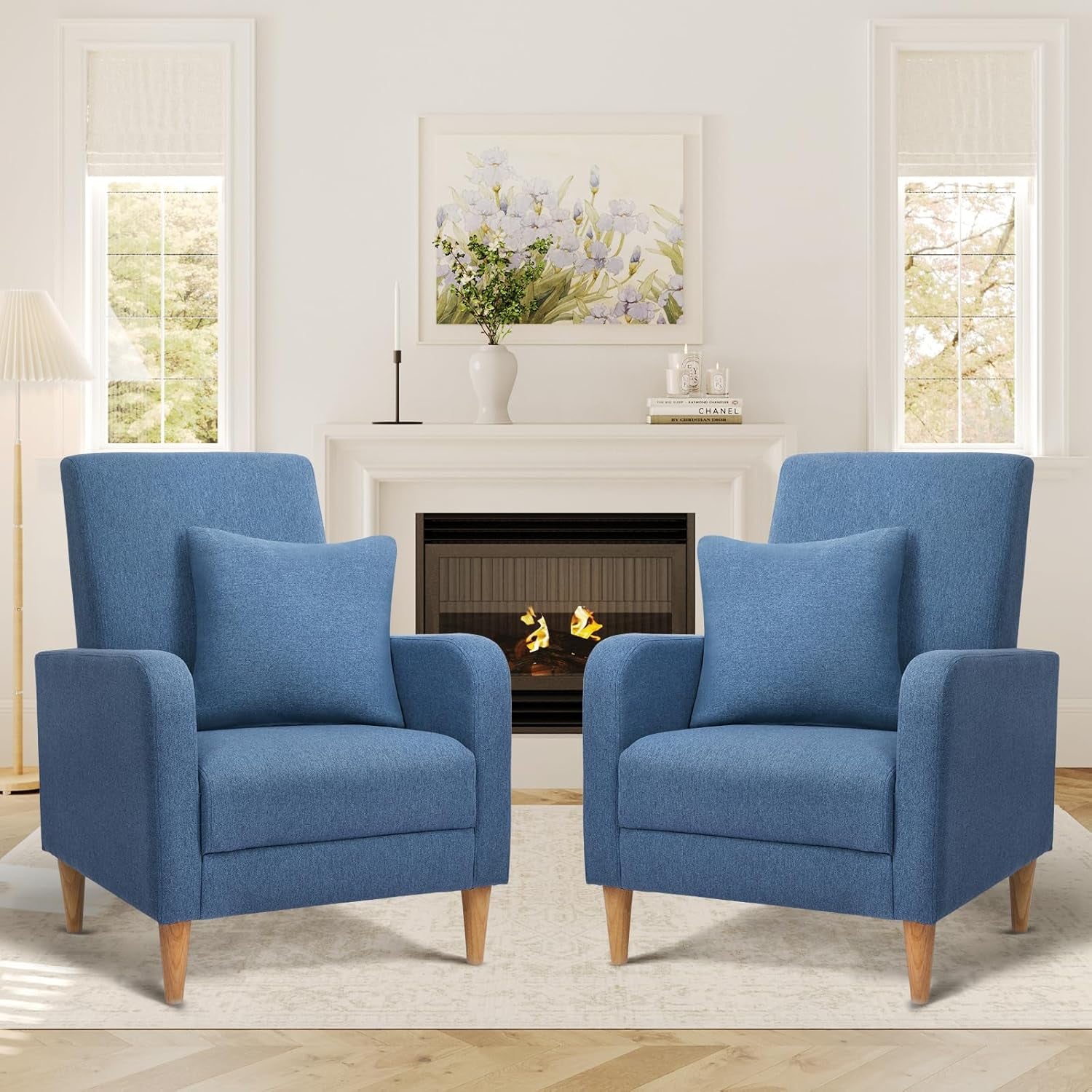 Two blue high-back upholstered armchairs with removable pillows and light wood tapered legs flanking a fireplace.