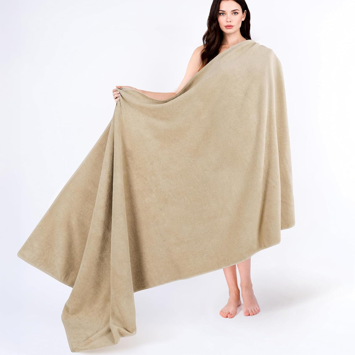 Model holding open a large beige towel draped across her body, towel spread wide to show size.