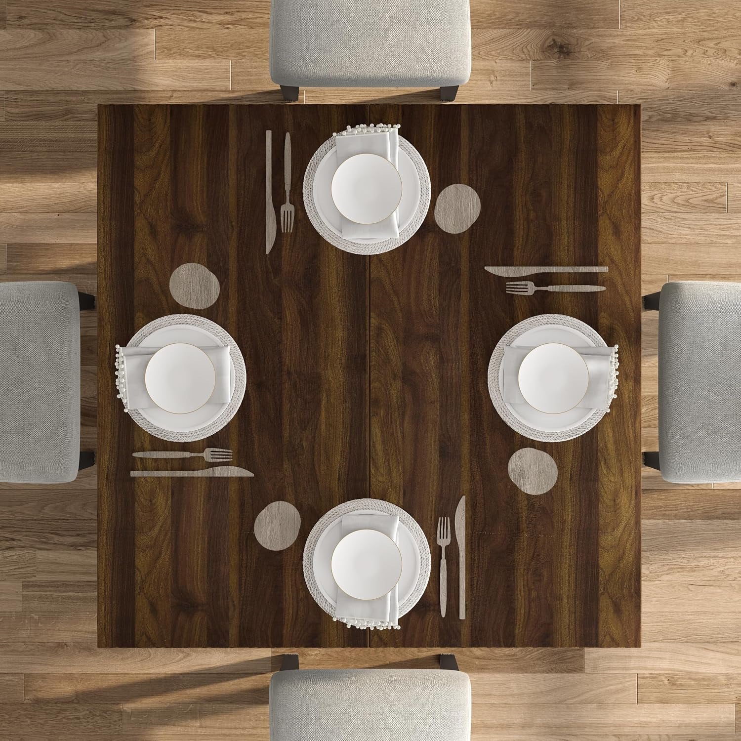 Top-down view of dark walnut square tabletop set for four with place settings on a wood floor