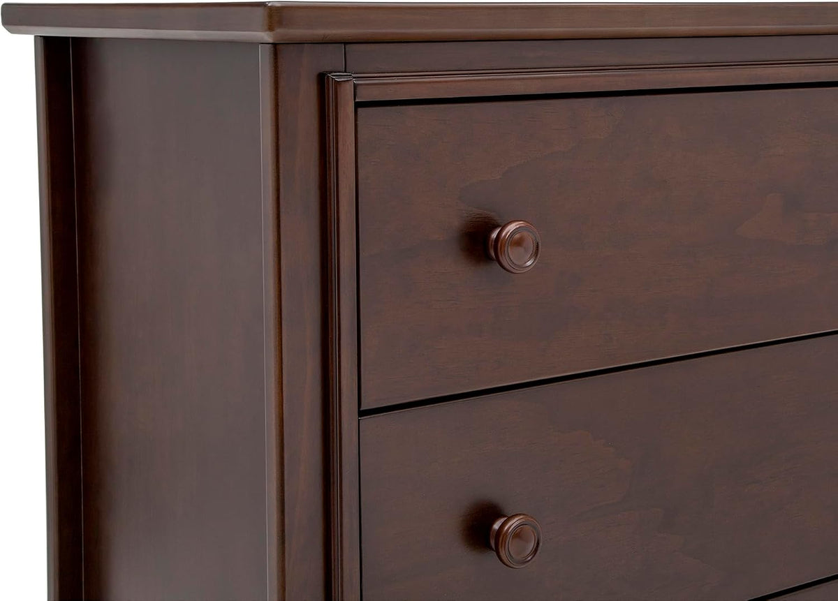 Close-up of walnut dresser corner showing two drawer fronts and round wooden knobs.