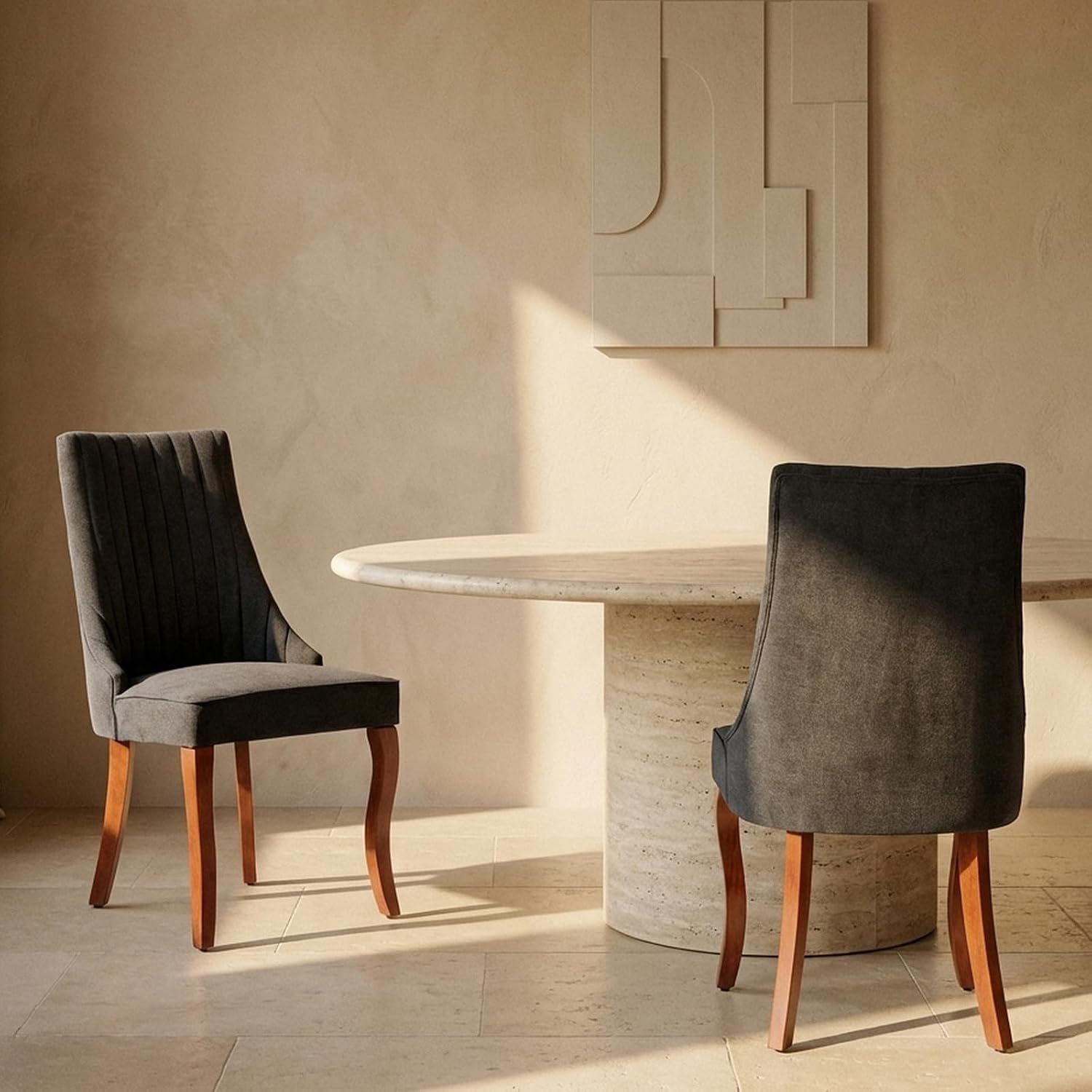 Side view of two charcoal upholstered high-back chairs by a round stone pedestal table.
