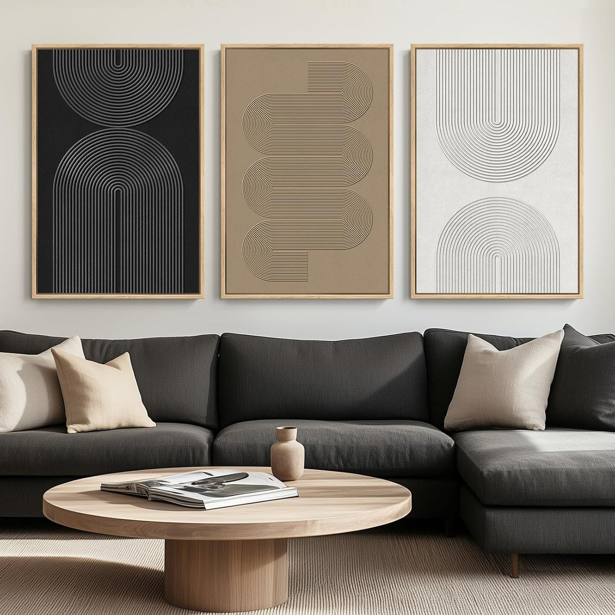Three framed geometric line prints in light wood frames over a dark sofa with a round wooden coffee table.