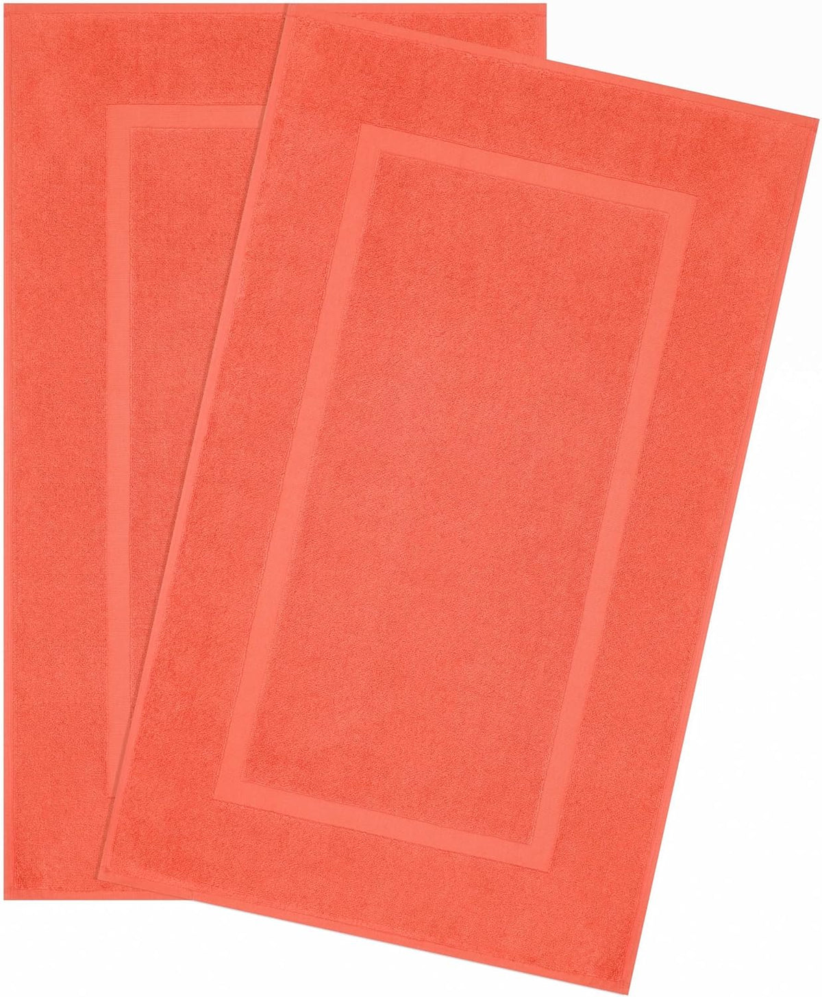 Two coral rectangular bath mats overlapped, showing a framed inset border and terry texture.