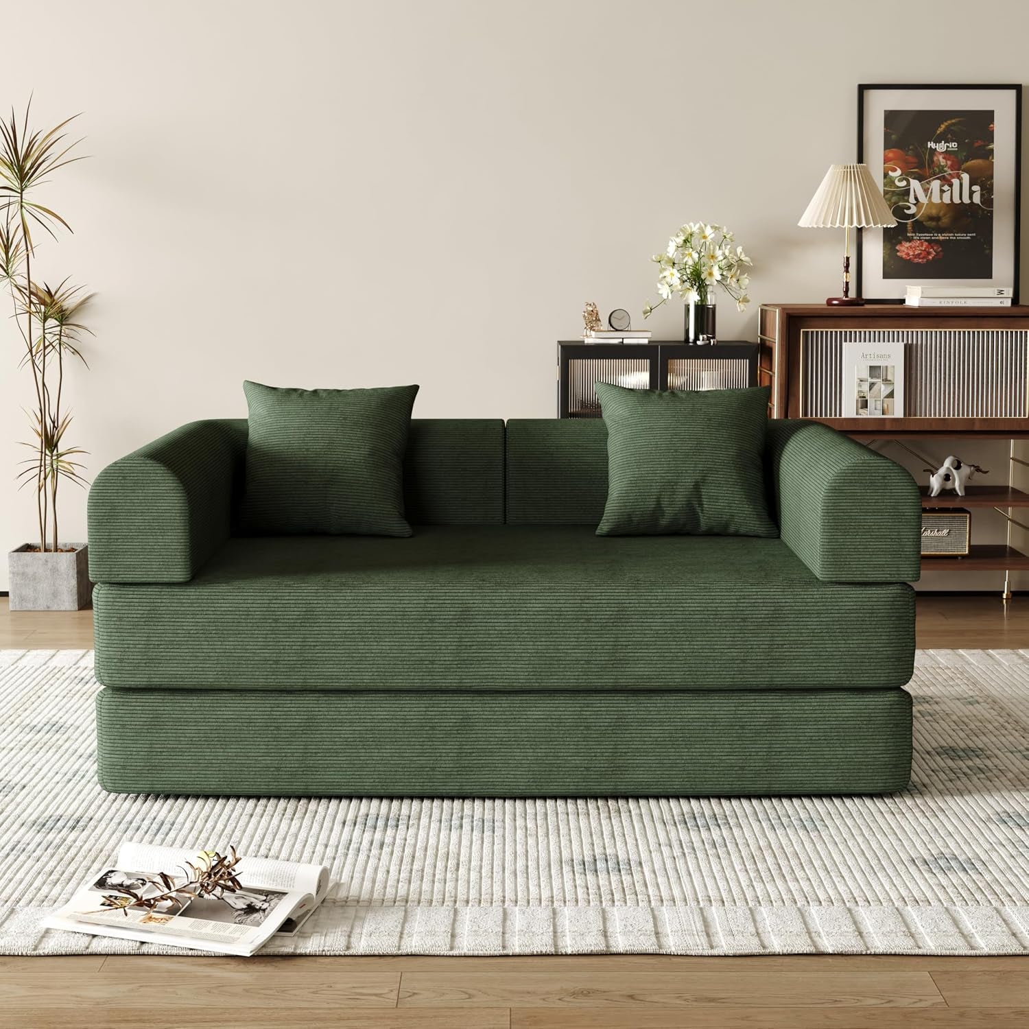 Front view of a dark green corduroy folding sofa with two matching square pillows in a living room.