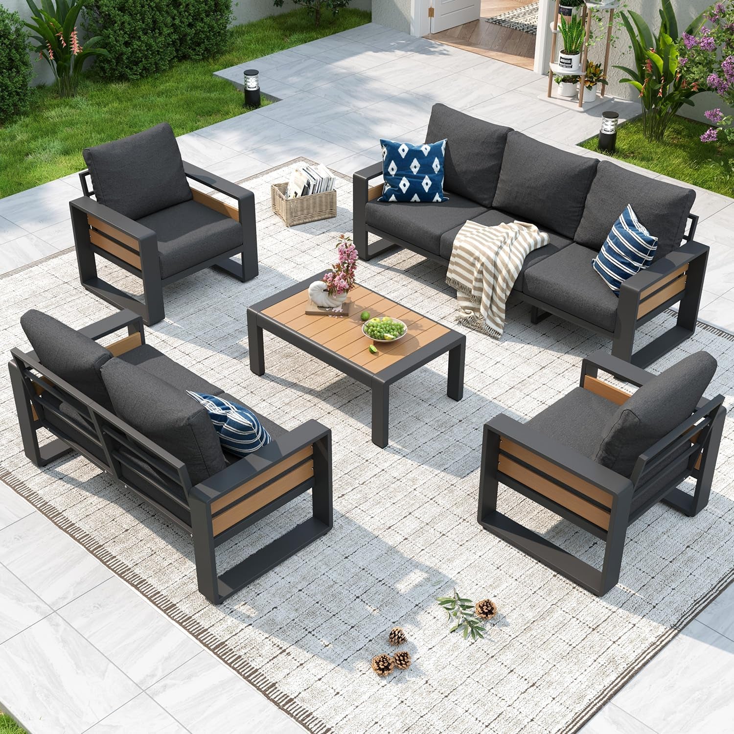 Outdoor patio sectional set arranged on a light rug: three-seat sofa, two single chairs, loveseat, and coffee table with