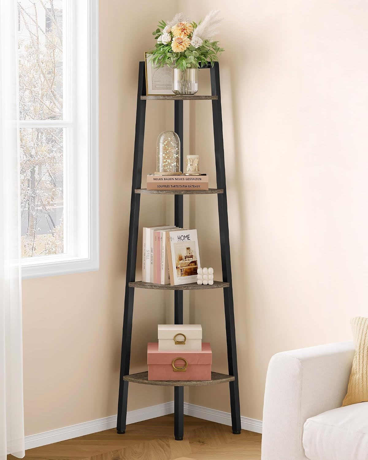 Black corner ladder shelf in a cozy corner with stacked boxes and decorative books