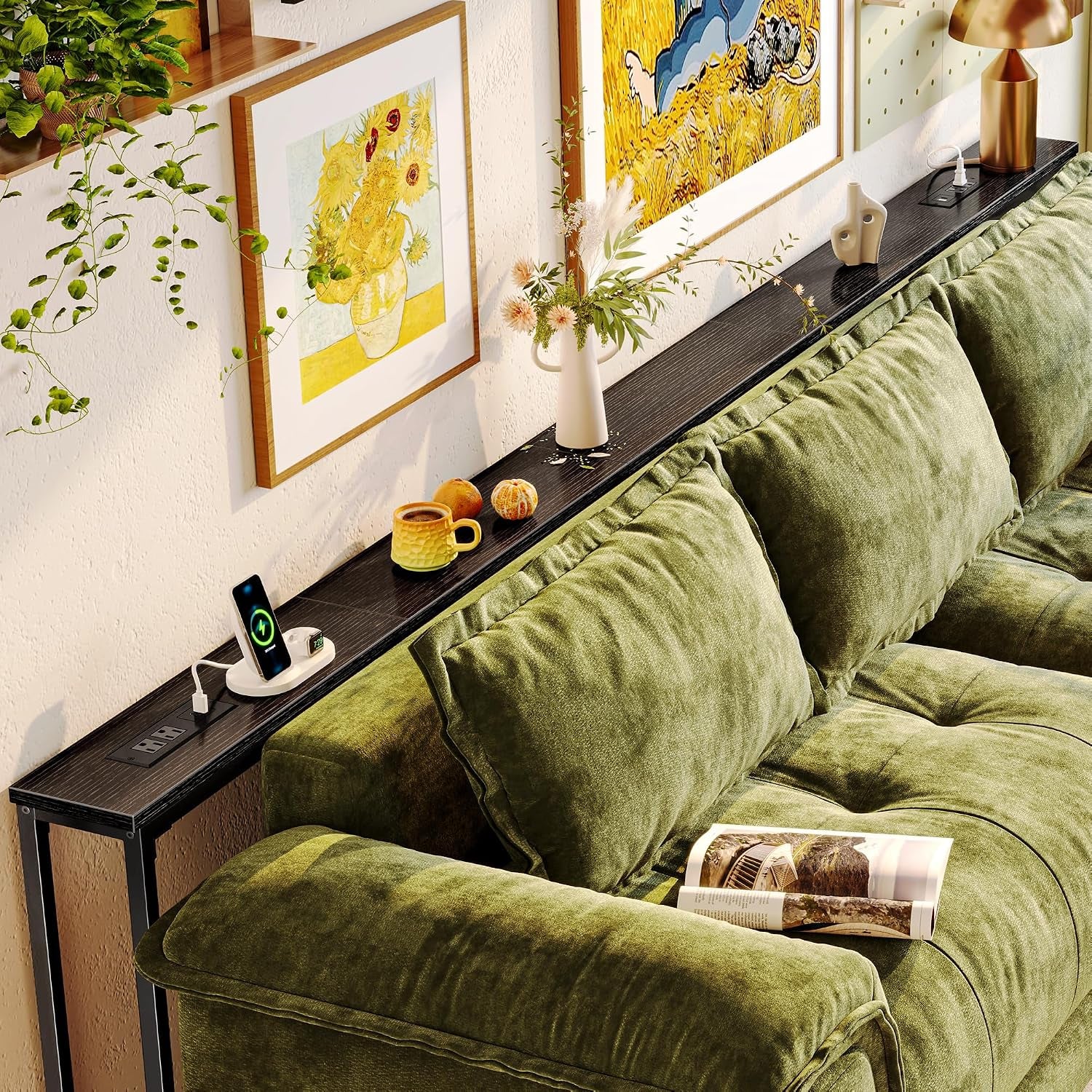 Close angled view of black narrow sofa table behind plush green sectional with decorative objects