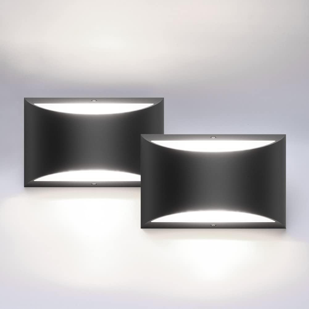 Two black rectangular wall sconces mounted on a pale wall, casting up-and-down warm light.