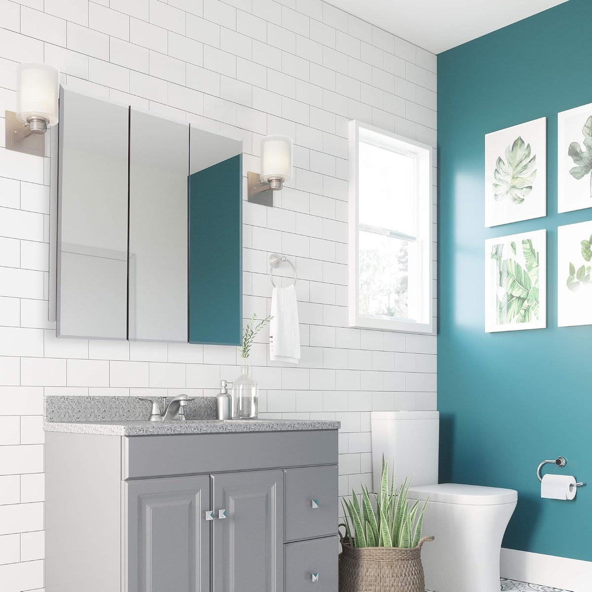 Three-panel mirrored medicine cabinet mounted above a gray vanity in a white-tiled bathroom with teal accent wall