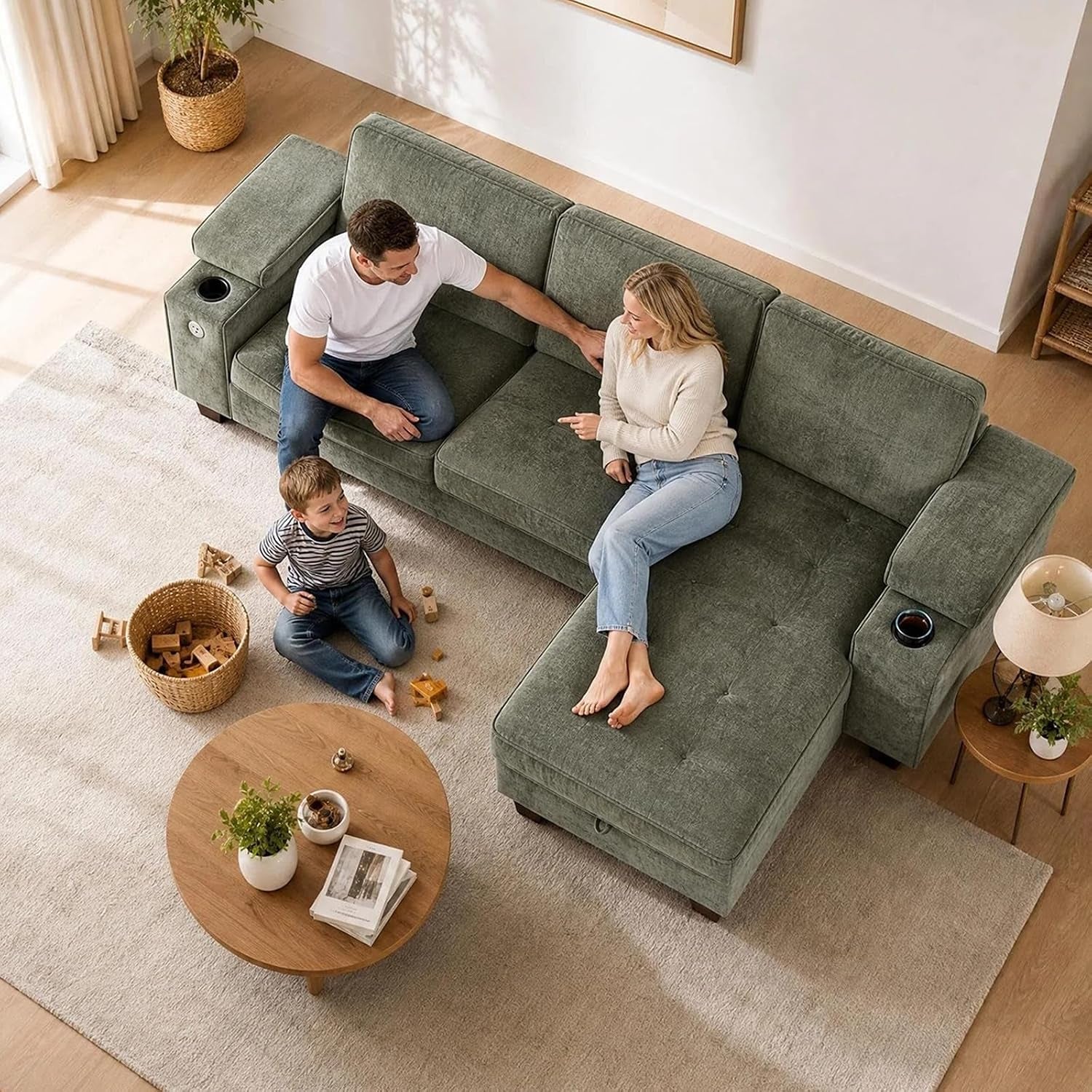 Aerial view of a green fabric L-shaped couch with two adults and a child, showing a cup holder in the armrest.