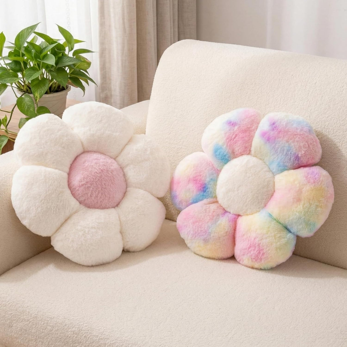Pair of fluffy flower pillows on a couch — one cream with pink center, one pastel rainbow with cream center.