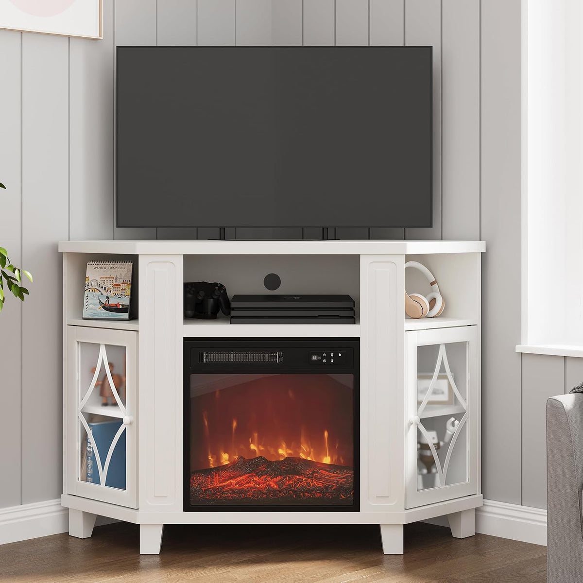 Front view of the white corner stand with a lit electric fireplace, TV on top, and accessories on the open shelves.