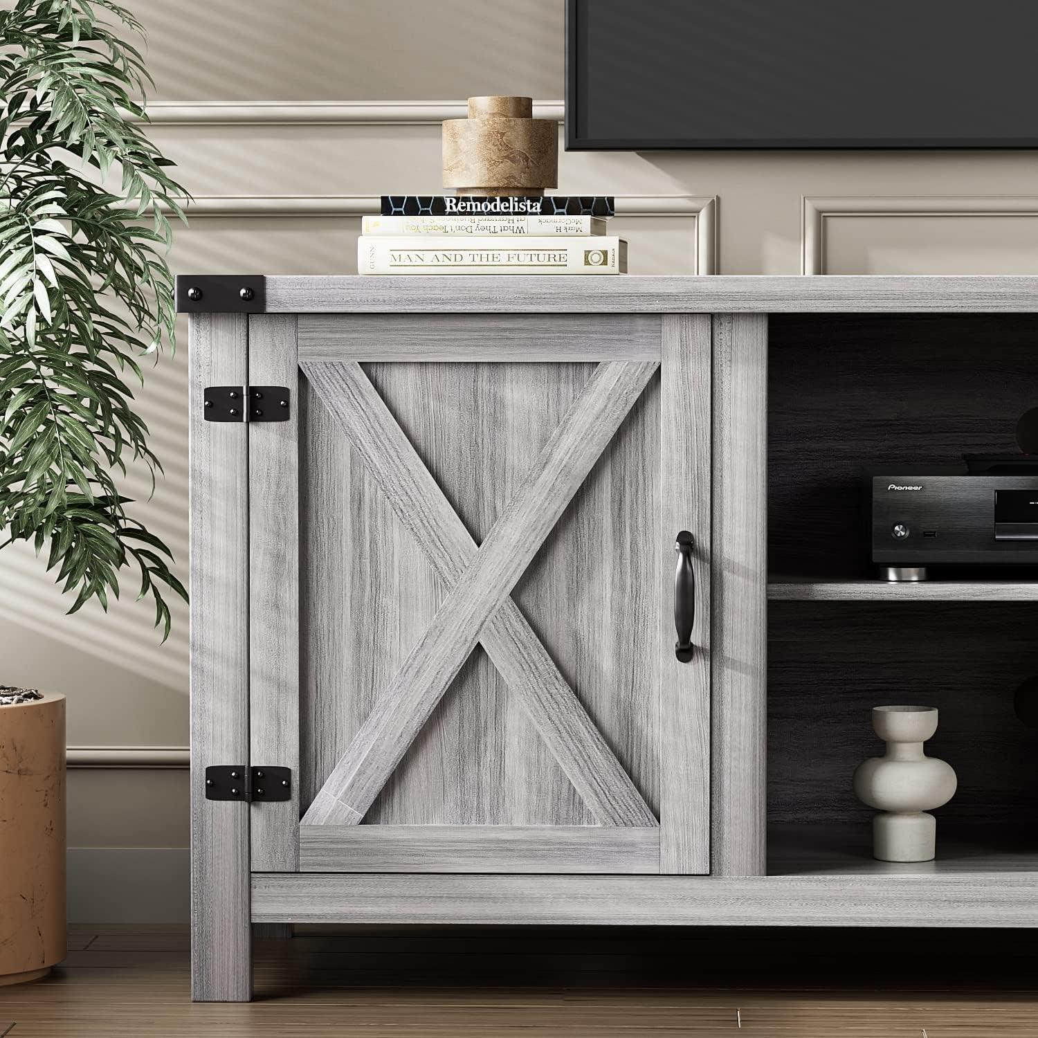 Three-quarter view of gray wash barn-door TV stand with a mounted TV above and circular rear cable hole visible.