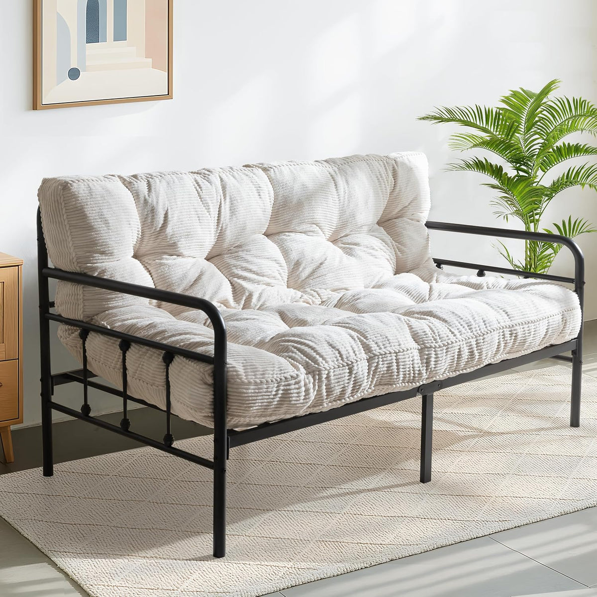 Off-white ribbed futon mattress fitted on a black metal daybed frame in a sunlit room.