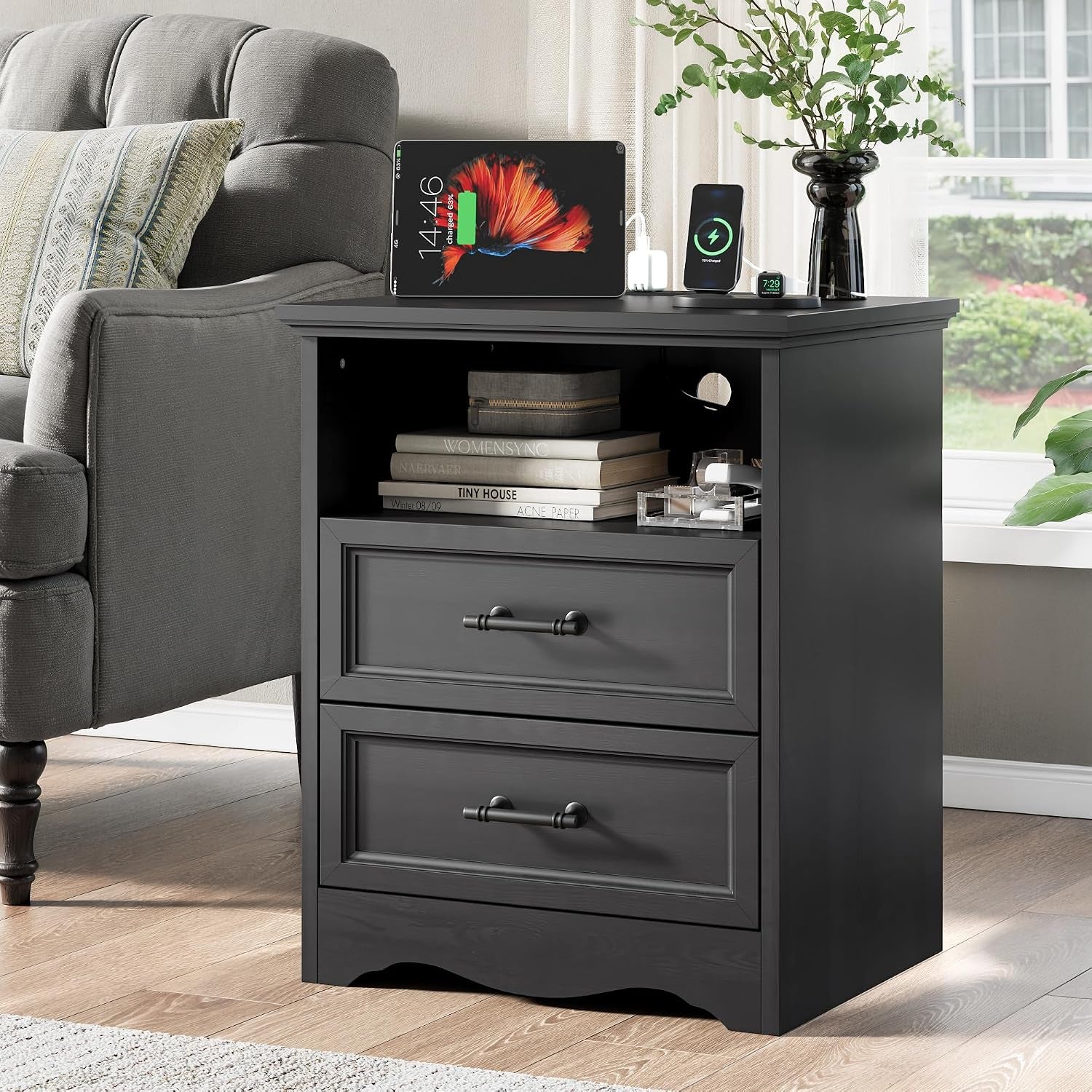 Black nightstand beside a sofa showing top surface with tablet and phone charging