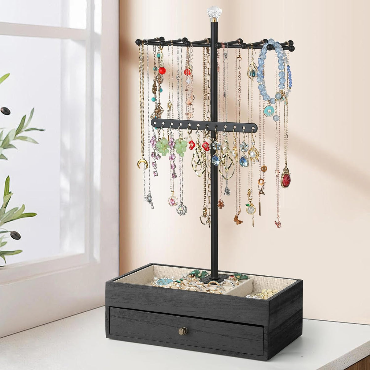 Full room-setting view of the black three-tier necklace tree on its wooden base with necklaces hanging