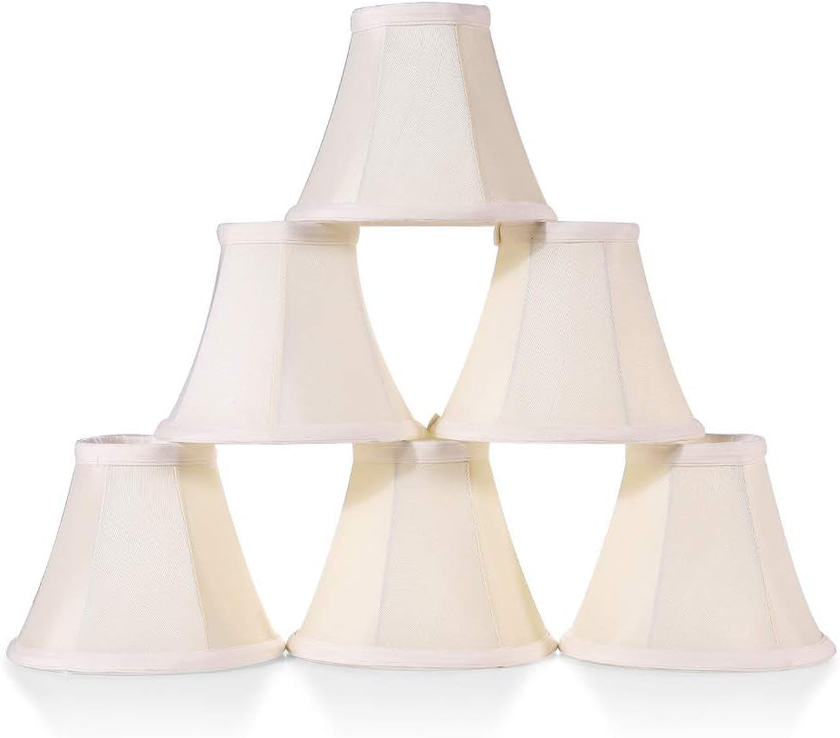 Six cream white bell-shaped clip-on lamp shades stacked in a pyramid on a white background