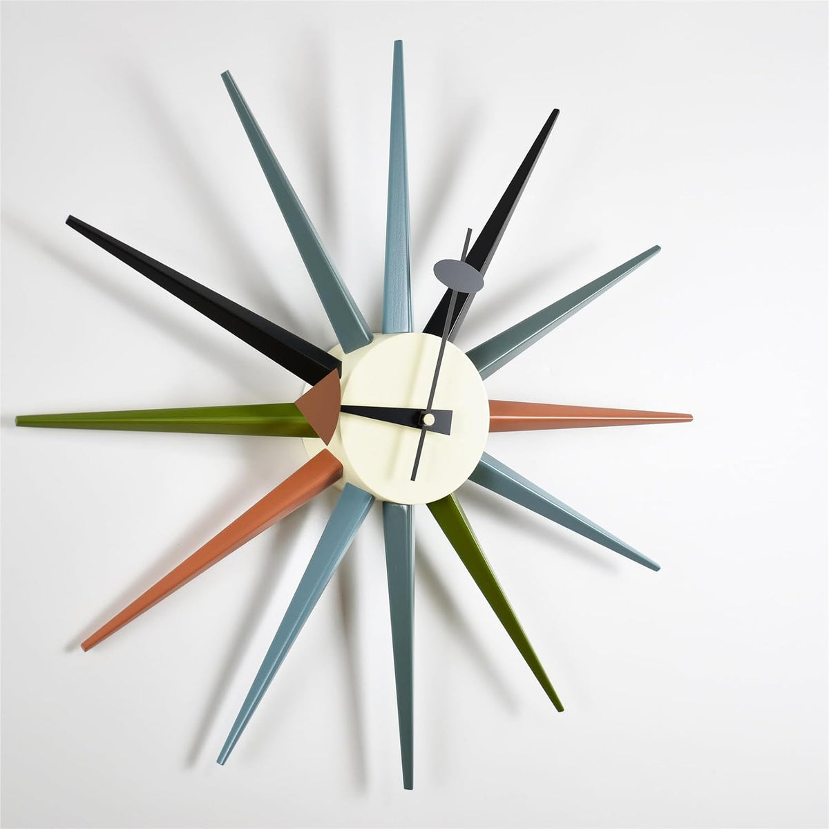 Close angled detail of the clock face showing cream center, black hands and long multicolor tapered wood spokes.